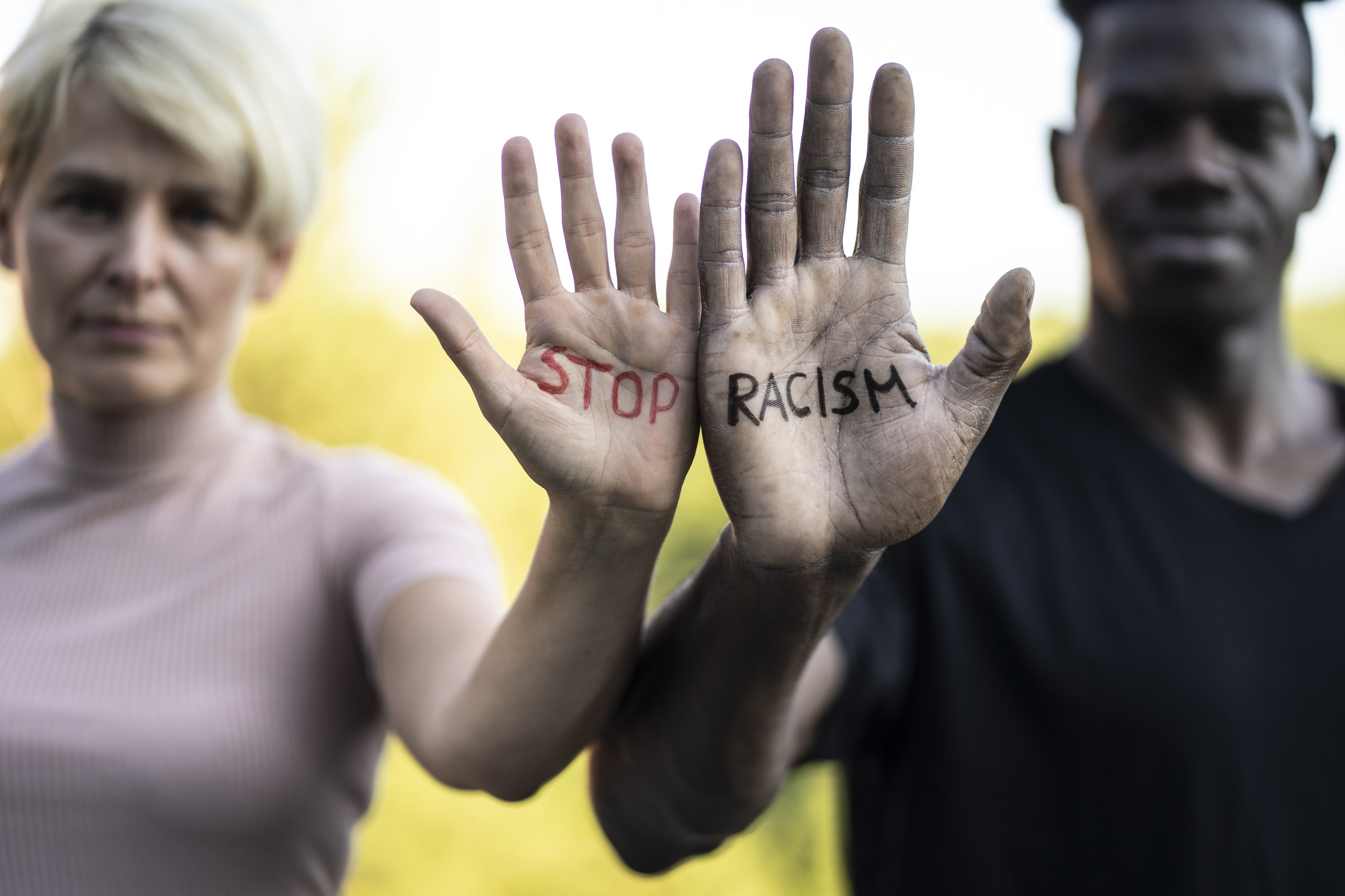 Multi-racial friends join hands to show &quot;Stop Racism&quot; writer on them. 