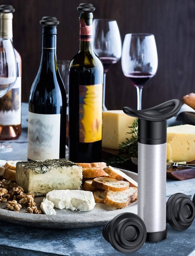The vacuum pump and stoppers next to wine and cheese 
