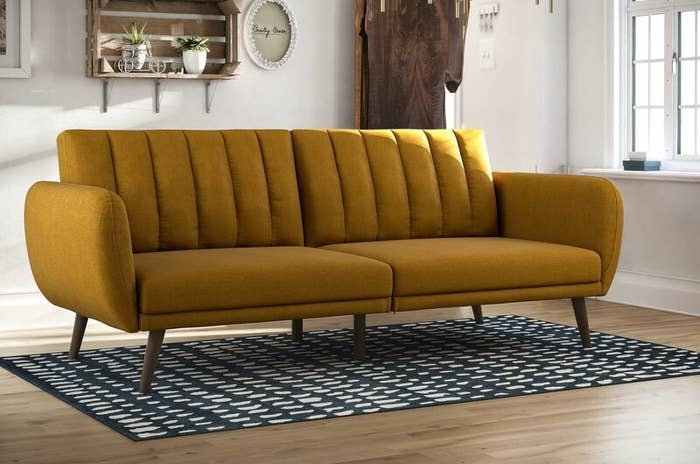 a mustard upholstered convertible couch in a living room