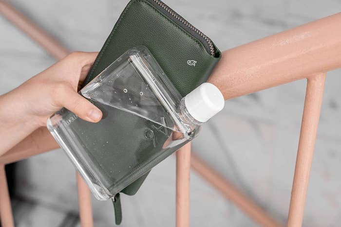 person holding the water bottle next to their wallet