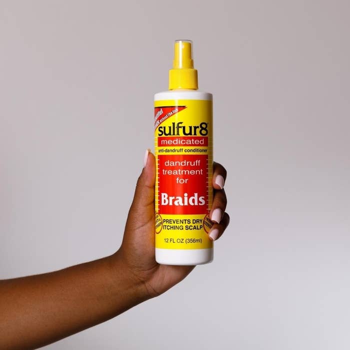 A person holding the bottle up against a wall