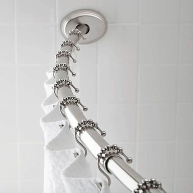 A close up of a curved shower rod with a curtain hung on it