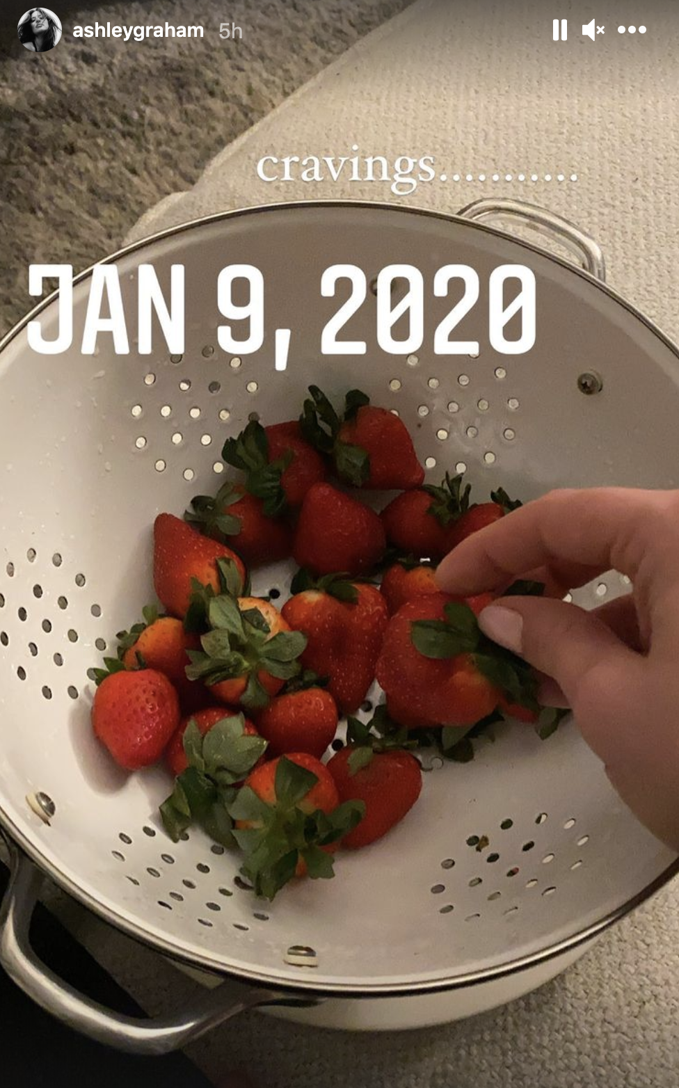Ashley reaching into a colander full of strawberries