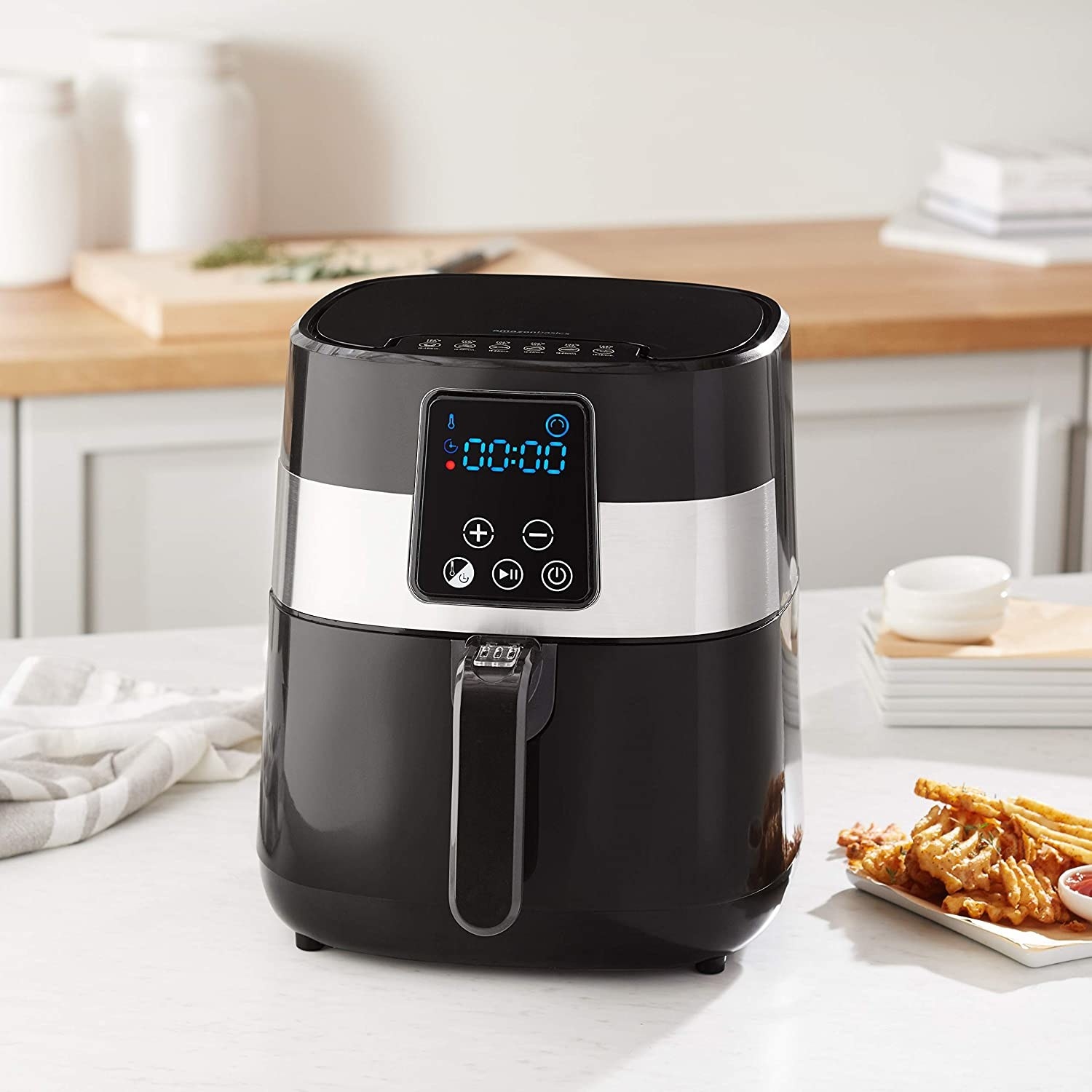 the air fryer on a table with a plate of fries next to it