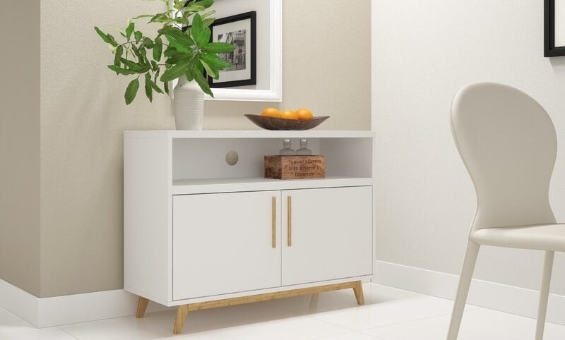 a white server drawer with two doors and a shelf, with wooden legs and handles