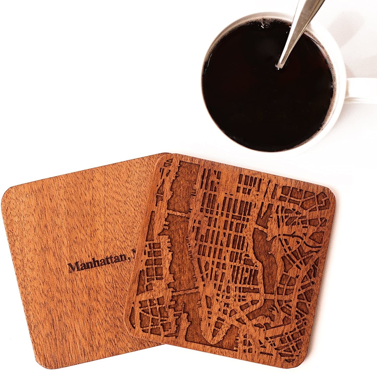 Brown Manhattan coasters sit beside a white cup of coffee