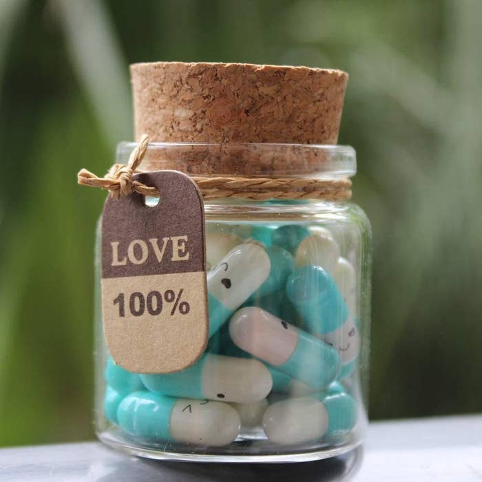 The corked bottle holding the blue capsules with a tag that says Love 100%