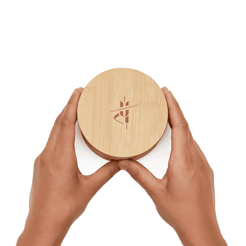 A gif a model removing the body stone from its reusable bamboo canister and applying it to their skin
