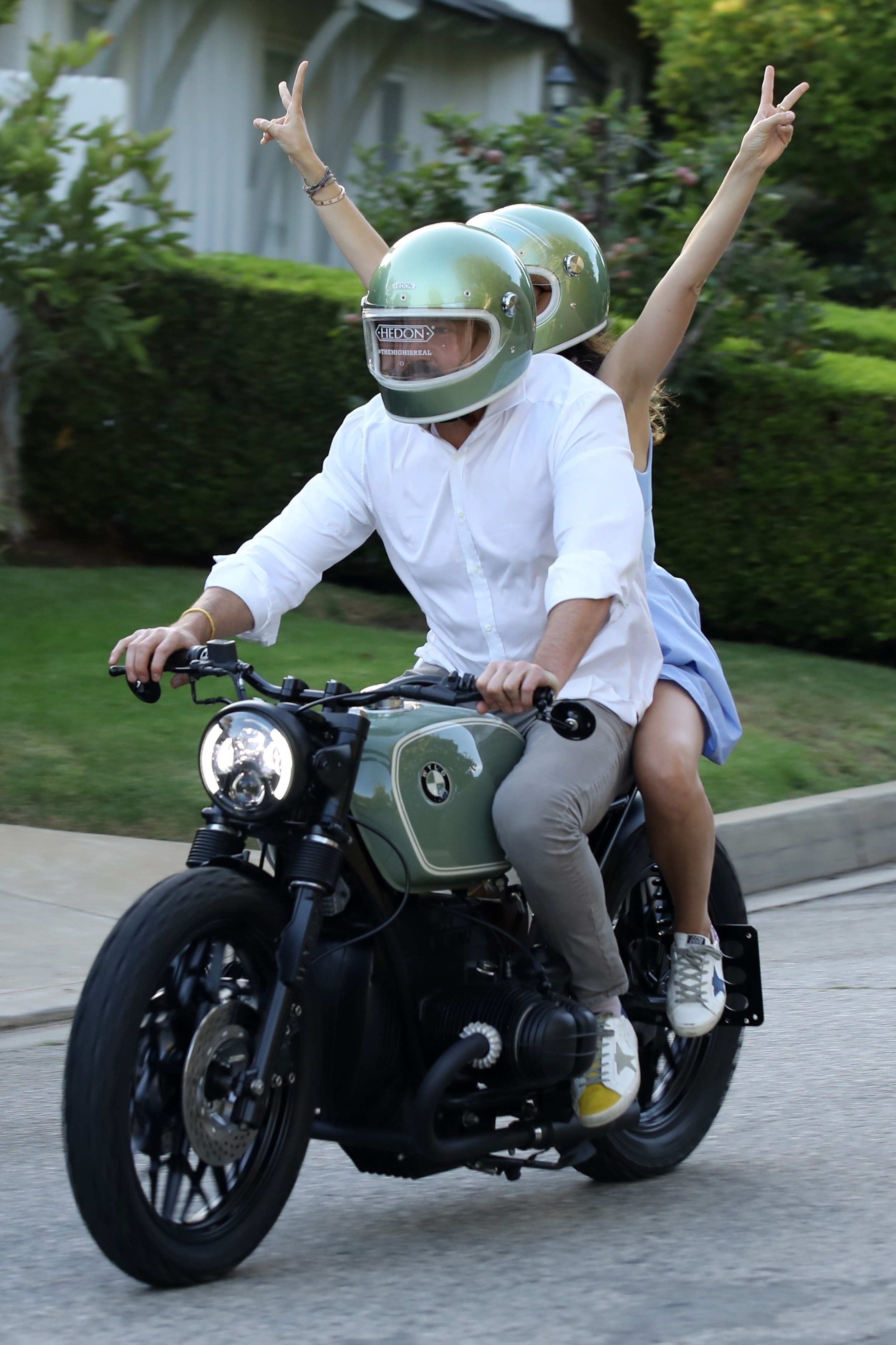 Ben Affleck and Ana de Armas riding a motorcycle as Ana holds both of her arms in the air and throwing the peace sign