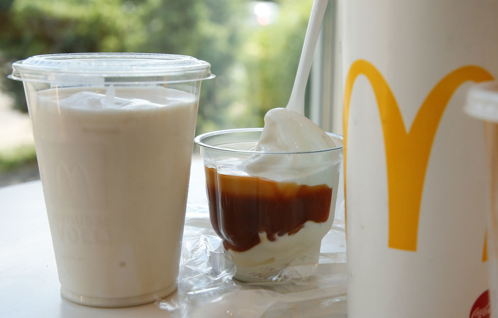 Plastic cup with a shake, a soft drink cup and a plastic cup with dessert on a table, taken in a McDonald&#x27;s