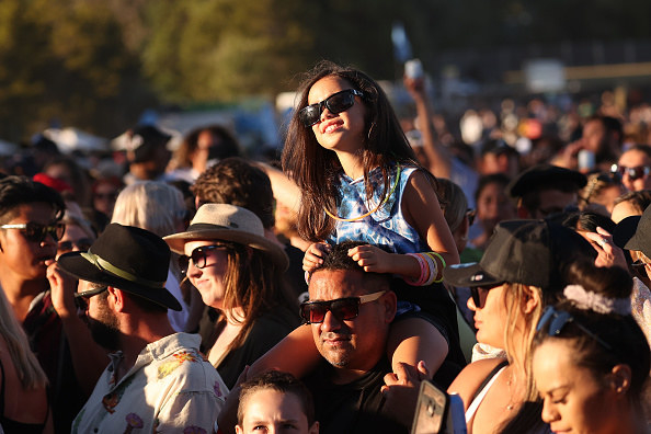 A girl sitting on a man&#x27;s shoulders enjoying the concert