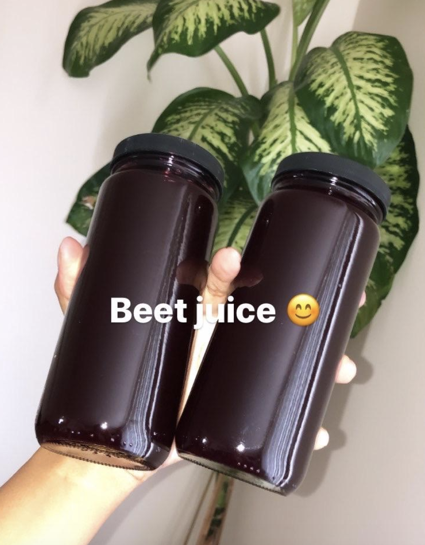 reviewer holding two bottles with beet juice inside