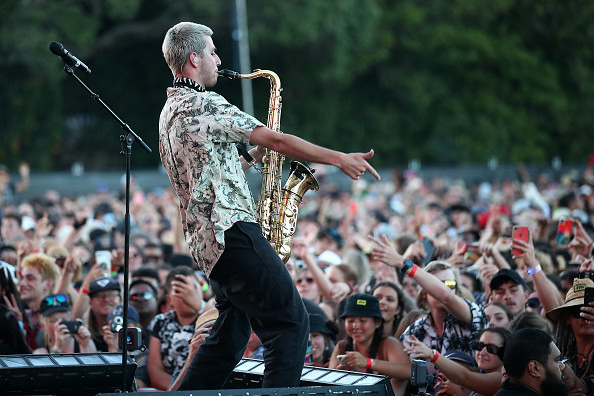 A man playing a saxophone to a massive crowd