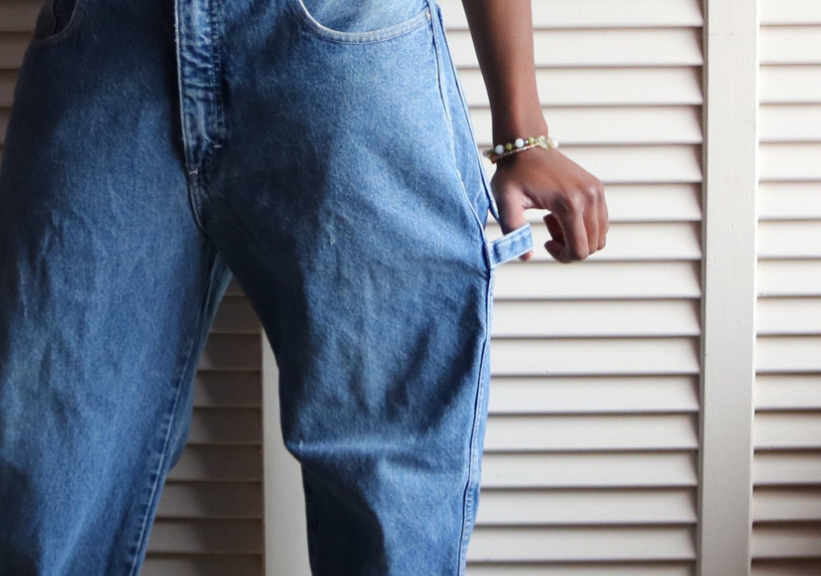 A person wearing carpenter jeans and pulling on the hammer loop