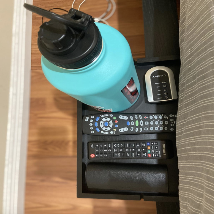 reviewer photo of shelf with remote controls and water bottle 
