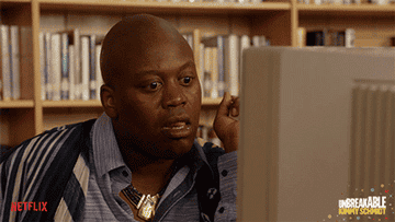 Titus Burgess in The Unbreakable Kimmy Schmidt reacting in shock as he sees something on a computer screen
