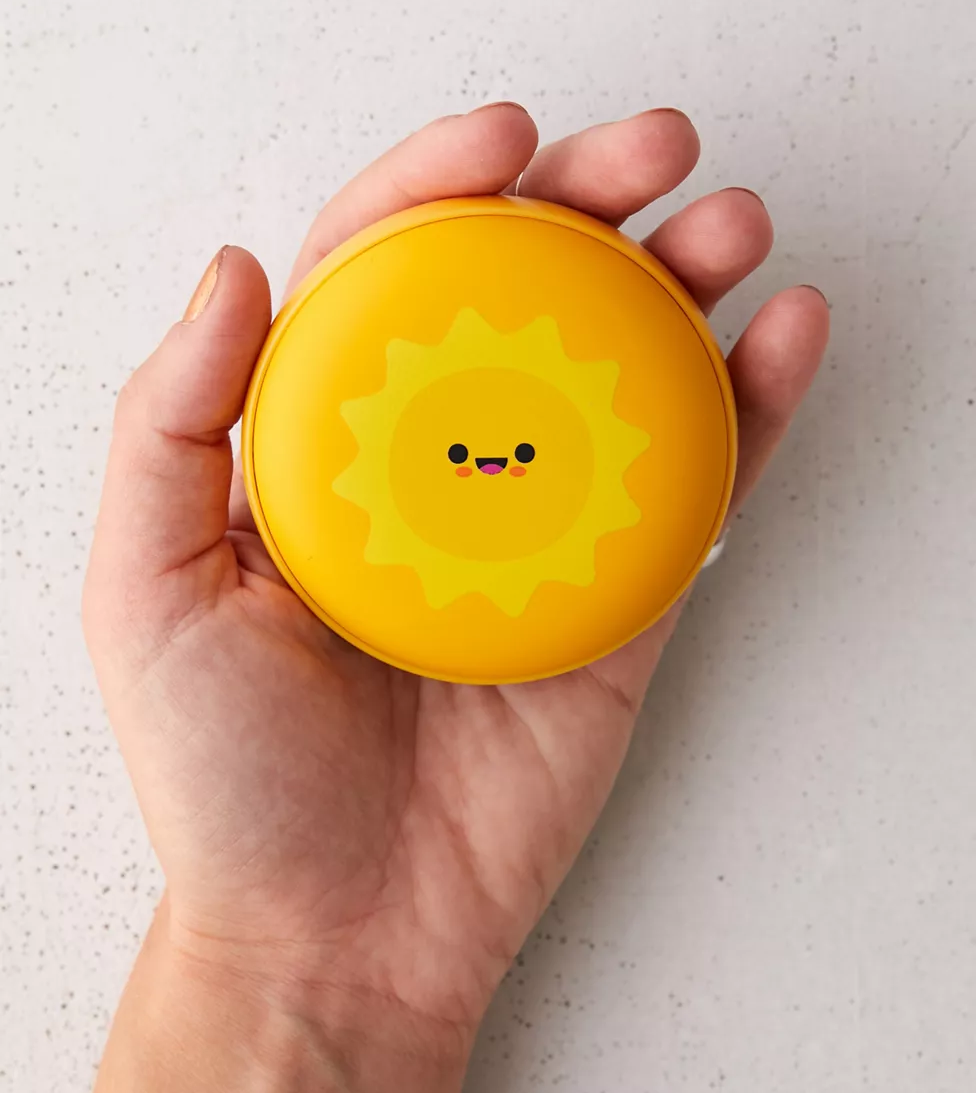 hand holds hand warmer with sun on it 