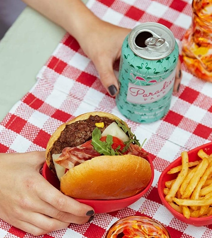 a hand holding a burger in the red bowl 