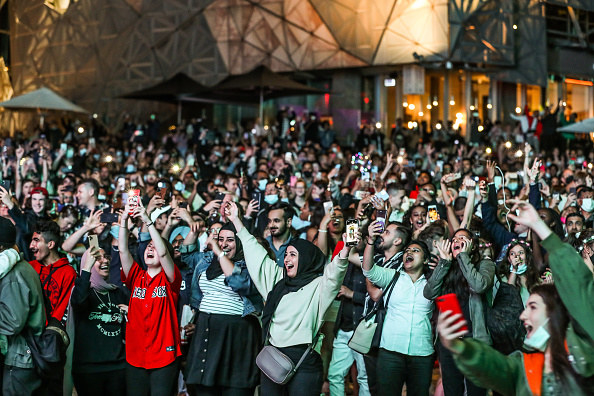 People in a large crowd raise their hands in celebration