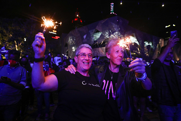 Two people holding on to each other while holding sparklers