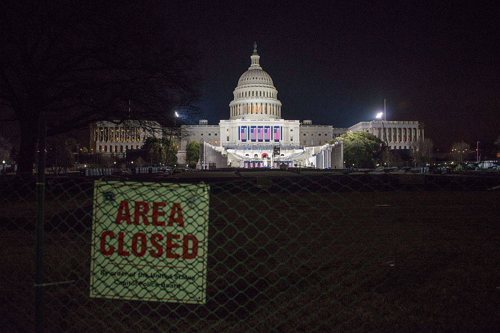 A sign on the chain-link fence warns &quot;Area Closed&quot; as the Capitol is illuminated in the background