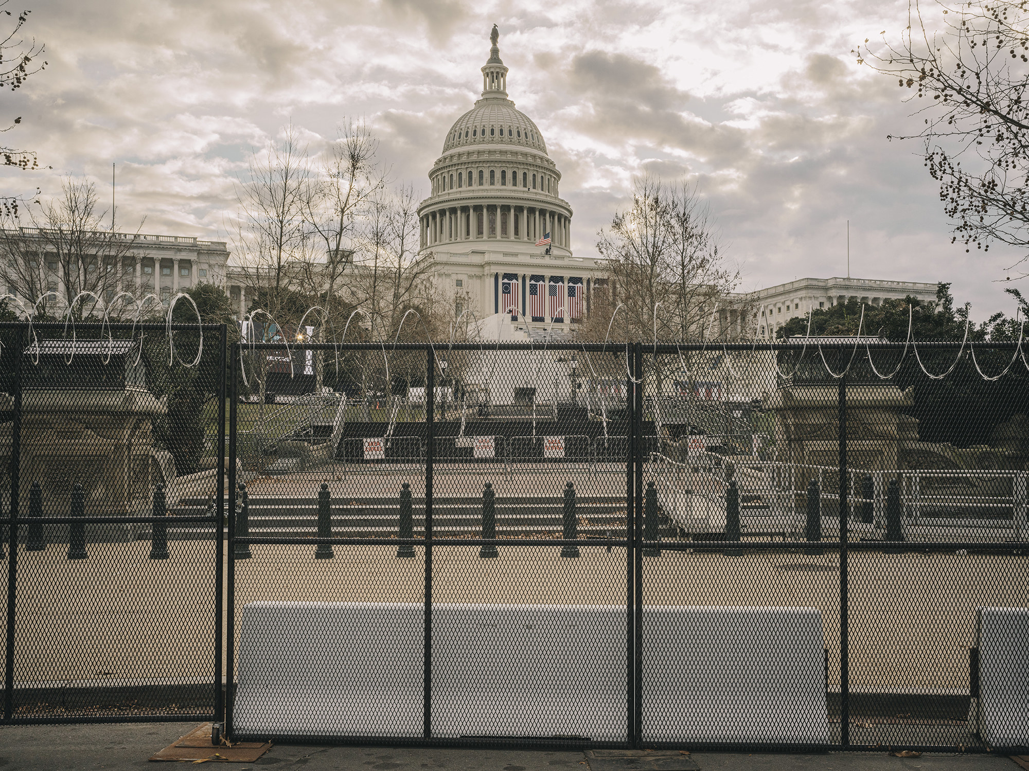 Razor wire lines a fence that runs around the Capitol building, which stands in the background