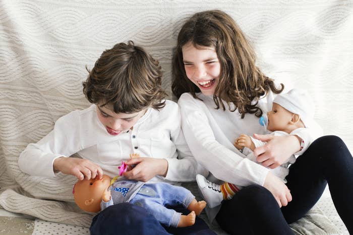 A boy and a girl playing with baby dolls