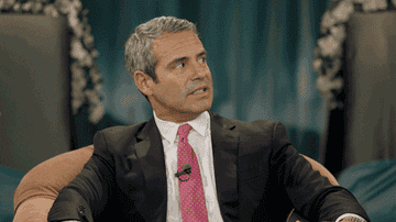 Andy Cohen grimaces and raises his eyebrows as he looks away on Inside Amy Schumer
