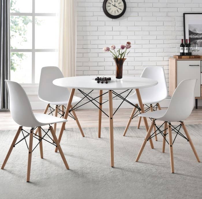 Round white table with wooden legs and matching white chairs