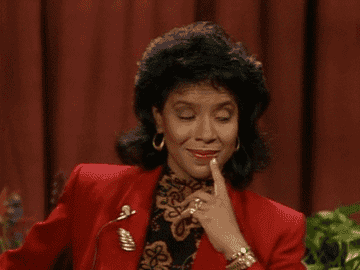 Clair Huxtable holds a finger to her chin as she looks sideways at someone on The Cosby Show