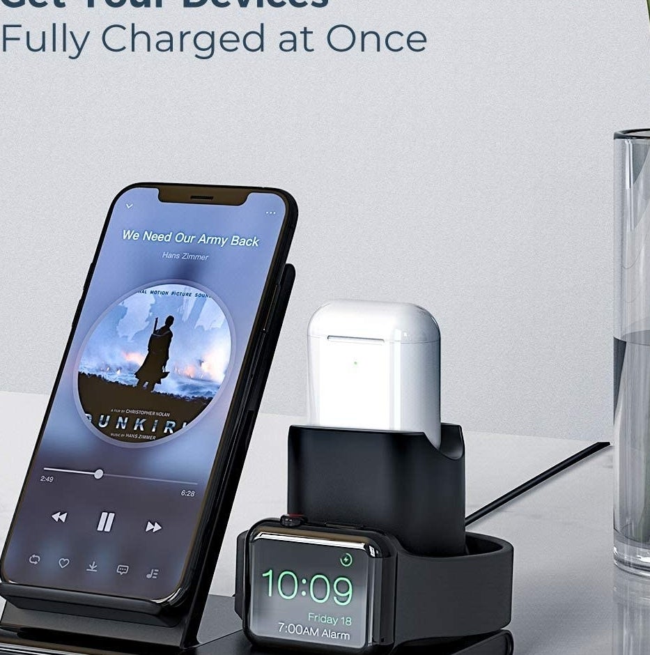 A phone, watch, and earbuds on the charging station