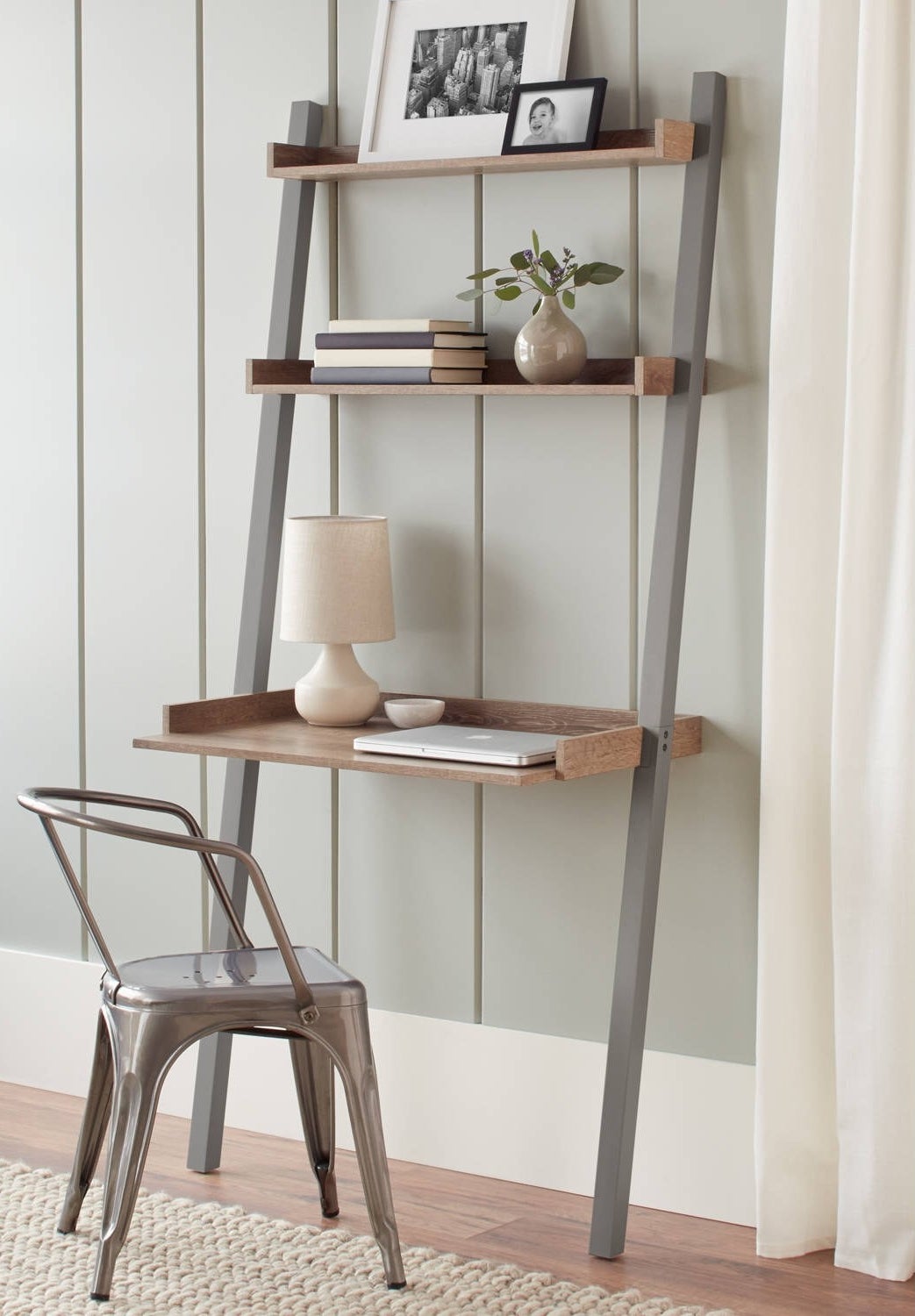 The gray leaning desk positioned against a wall in a home office