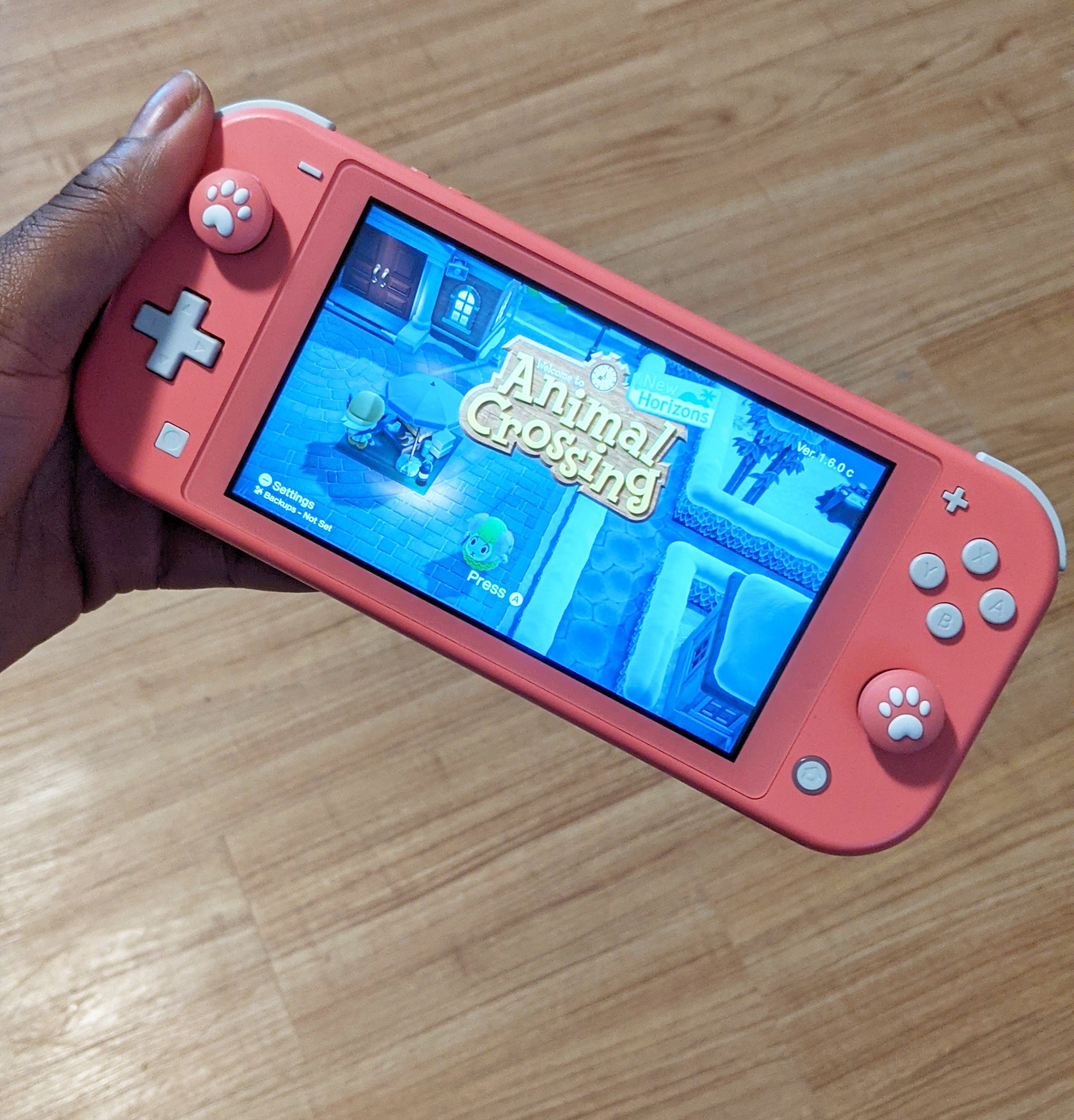 A person holding a Switch Lite console with silicone covers on the joysticks