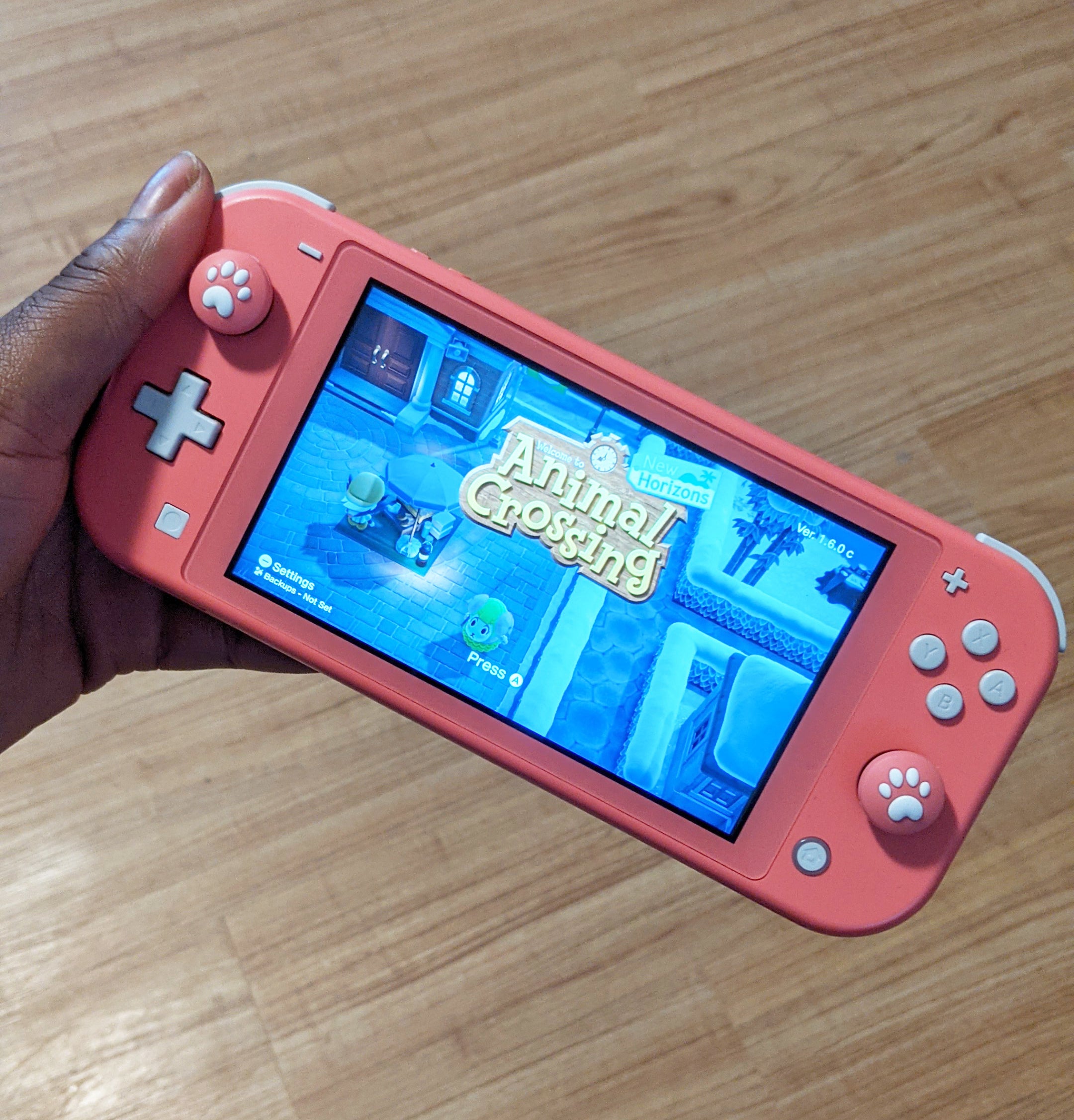 A person holding a Switch Lite console with silicone covers on the joysticks