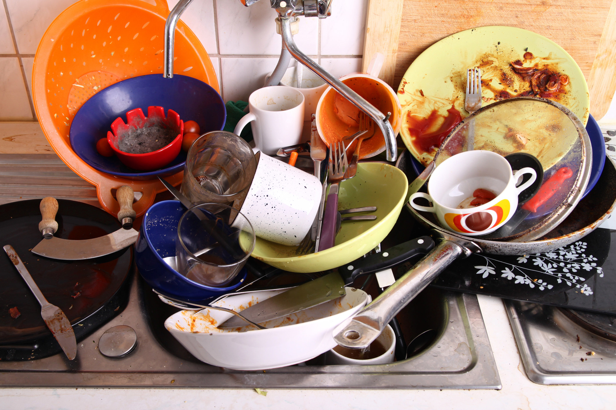 Huge pile of dirty pots, pans, cups, and dishes in the sink waiting to be washed