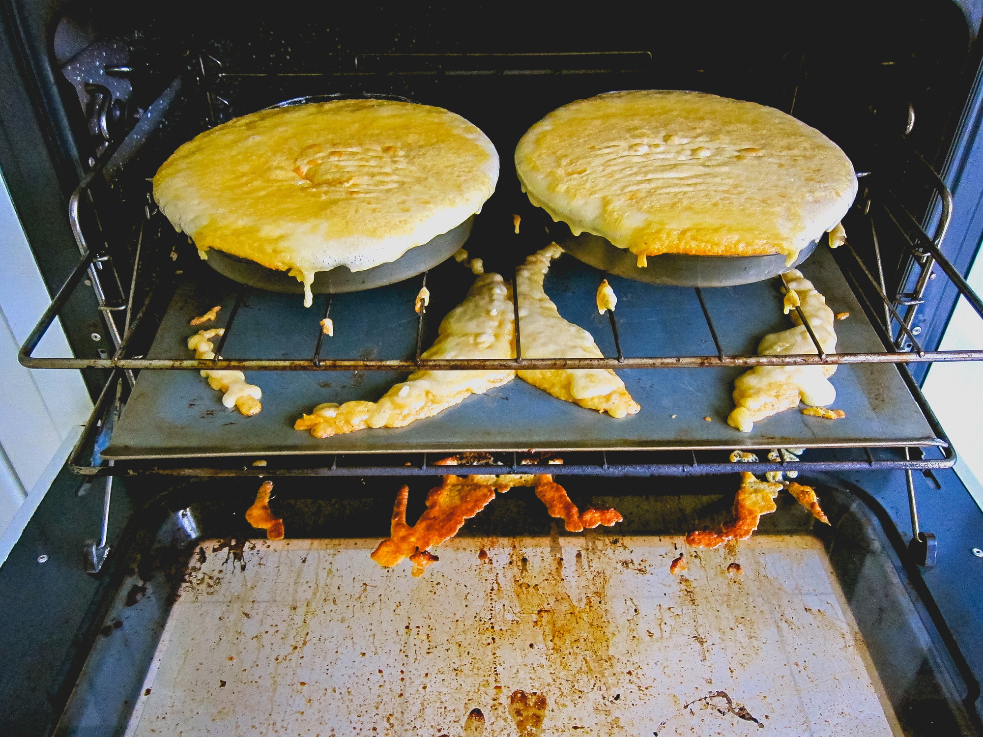 A messy cake being baked in the oven, drizzling all over the place