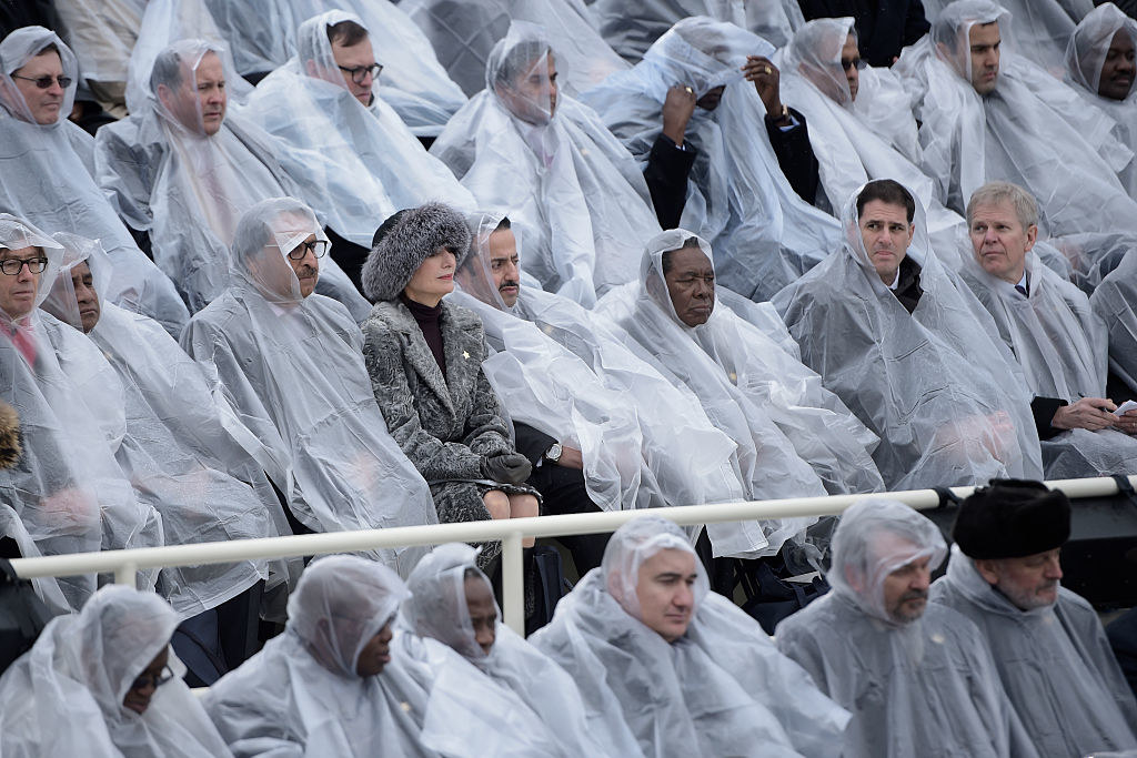 Guests wearing plastic rain ponchos with one woman wearing a fur hat and matching coat