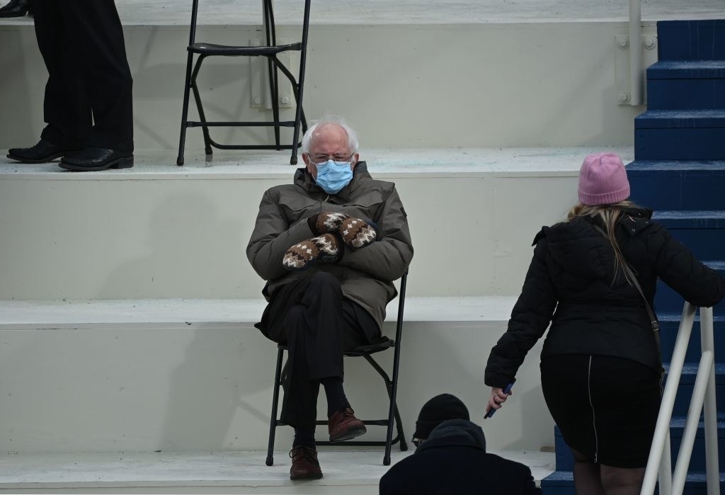 Bernie Sanders sitting cross-legged and six feet away from other guests with his face mask and gloves on