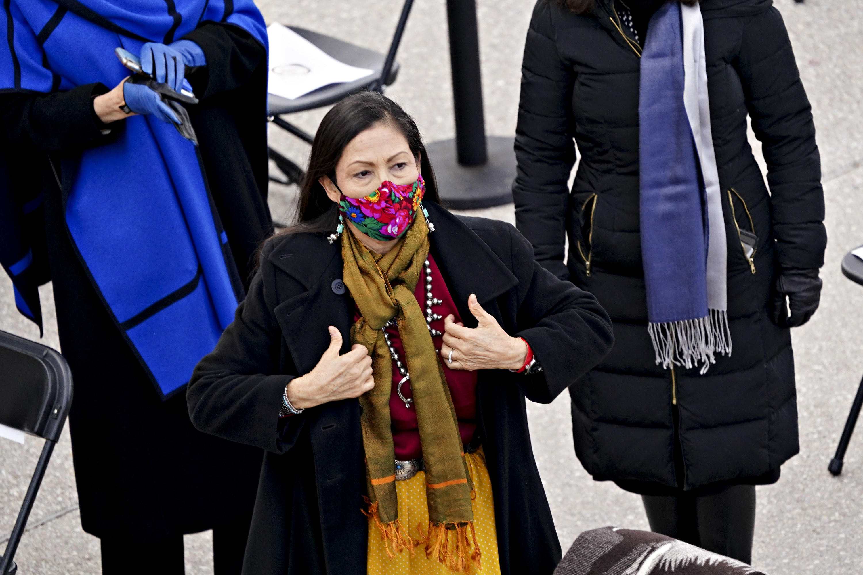 Representative Deb Haaland standing, in a floral face mask and yellow scarf, at the inauguration. 