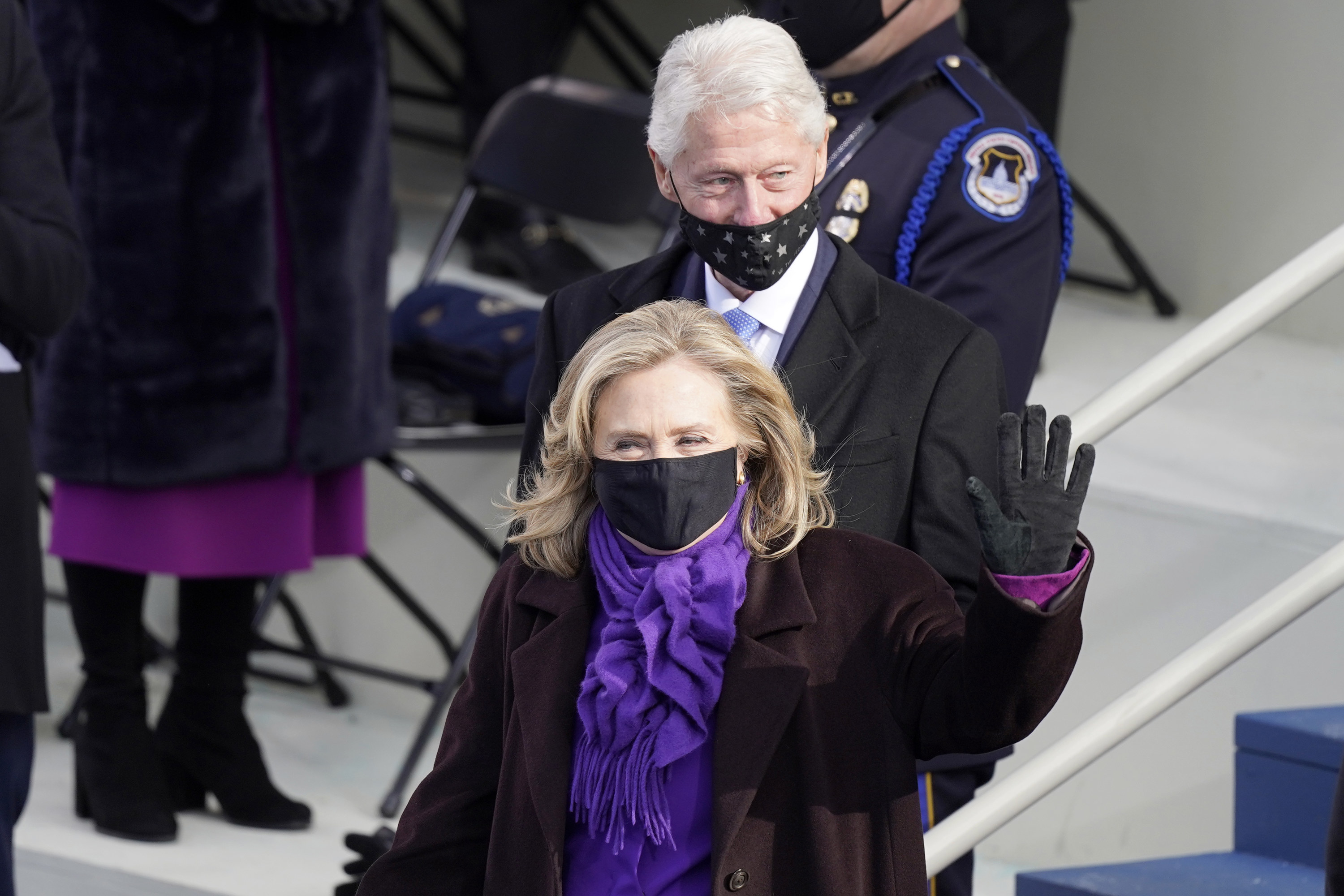 Bill Clinton with a star mask on only his chin and mouth and Hillary Clinton in a black face mask at the inauguration. 