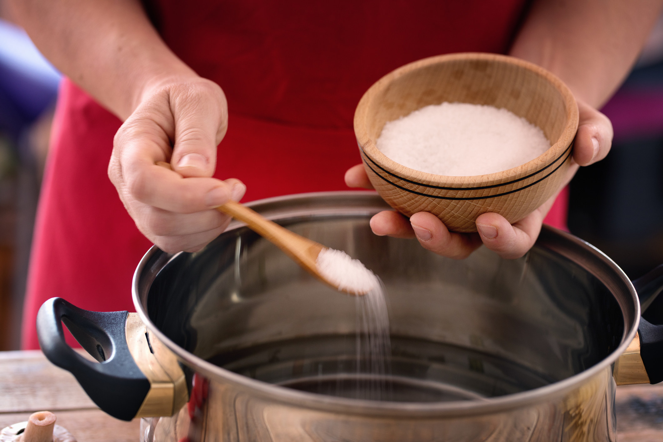A chef pouring salt into a pot of boiling water