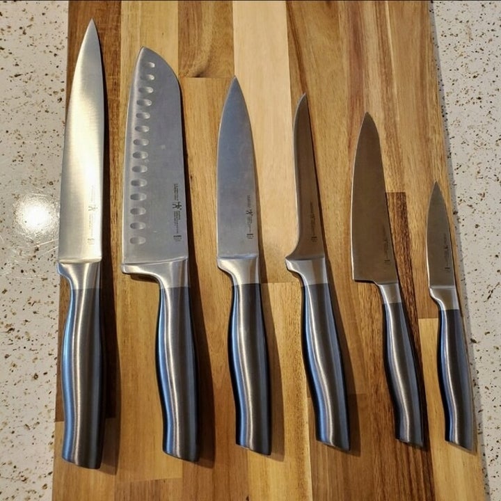 six kitchen knives resting on a butcher block
