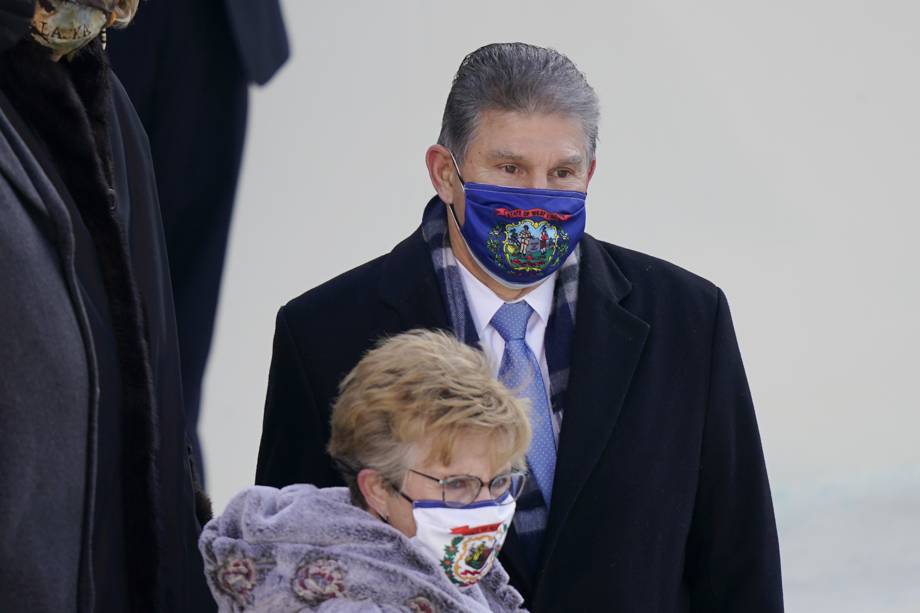 Sen. Joe Manchin and a woman wearing face masks with the state of West Virginia flag at the inauguration. 