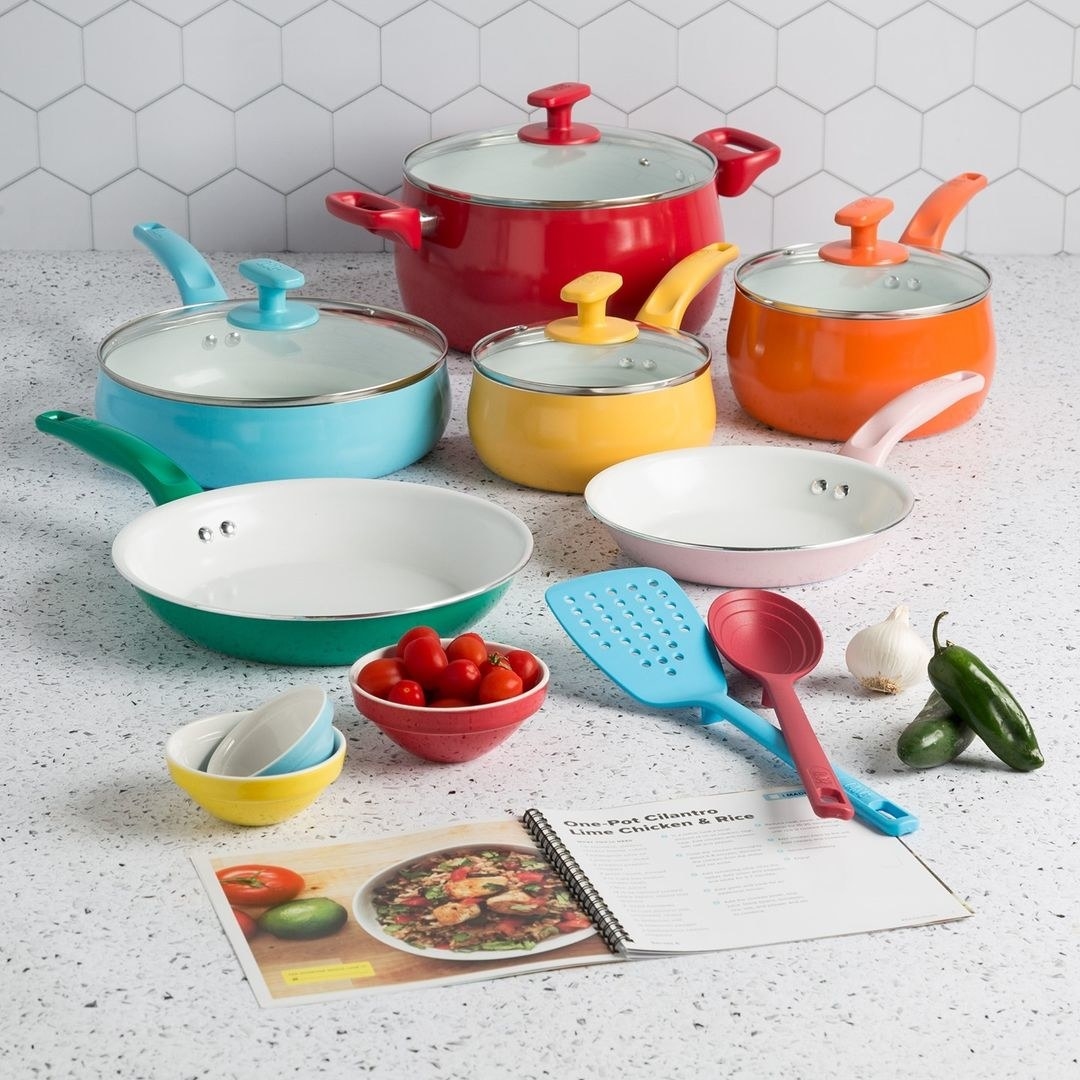 A bunch of pots and pans on a counter with a recipe book and pinch bowls