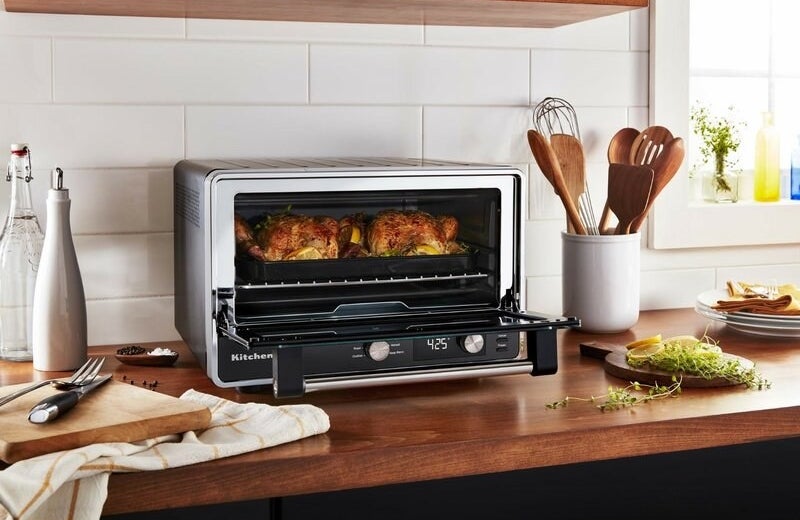a silver and black toaster oven with a digital screen with chicken on its rack
