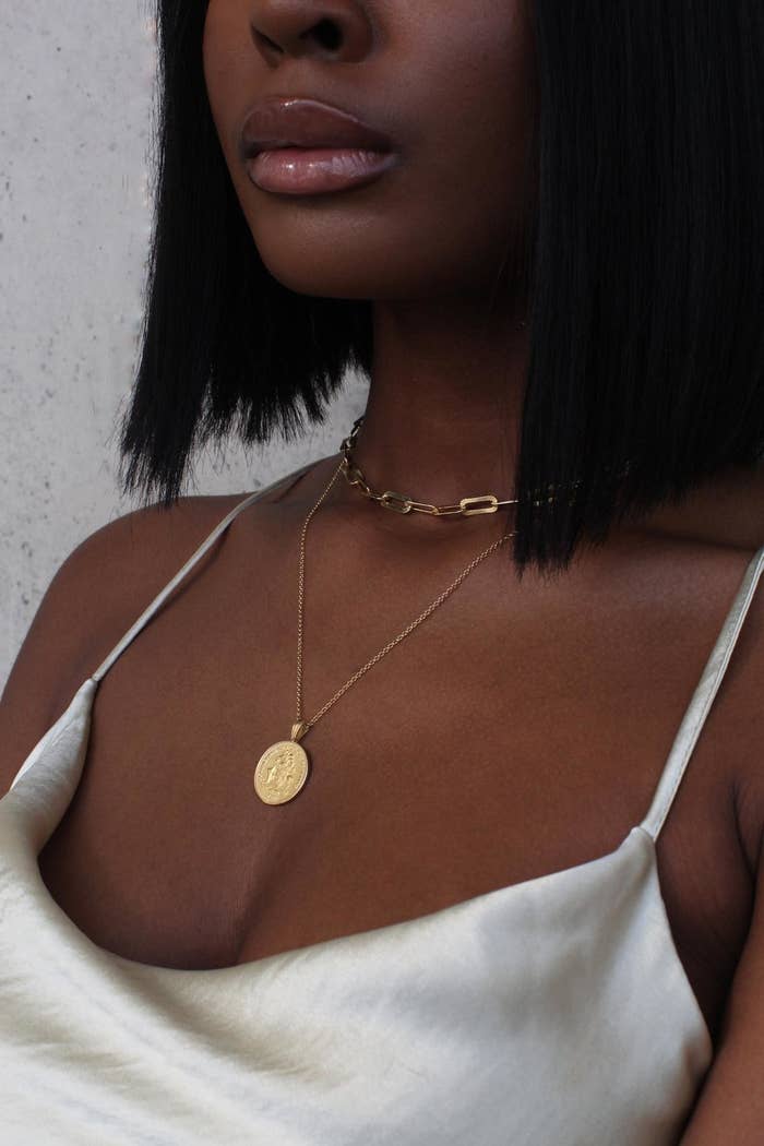 A person wearing the coin necklace layered with a chain lined choker 
