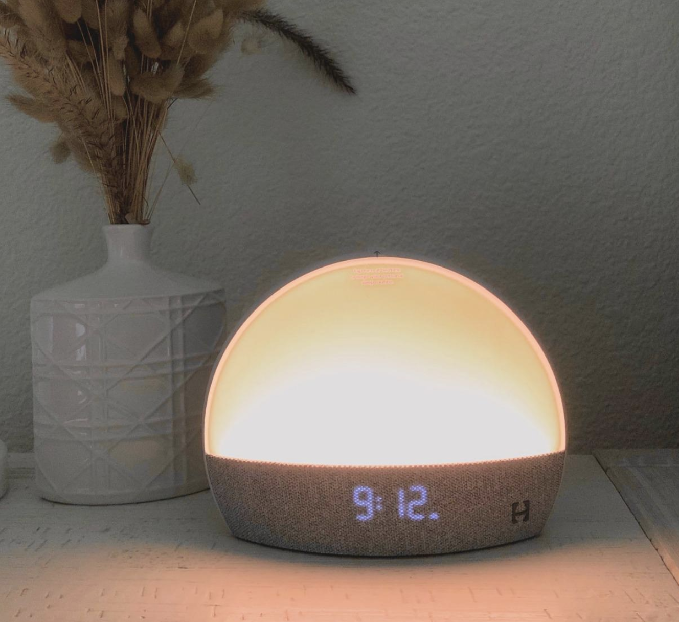 reviewer image of dome shaped amber light with digital clock on bottom  on a bedside table 