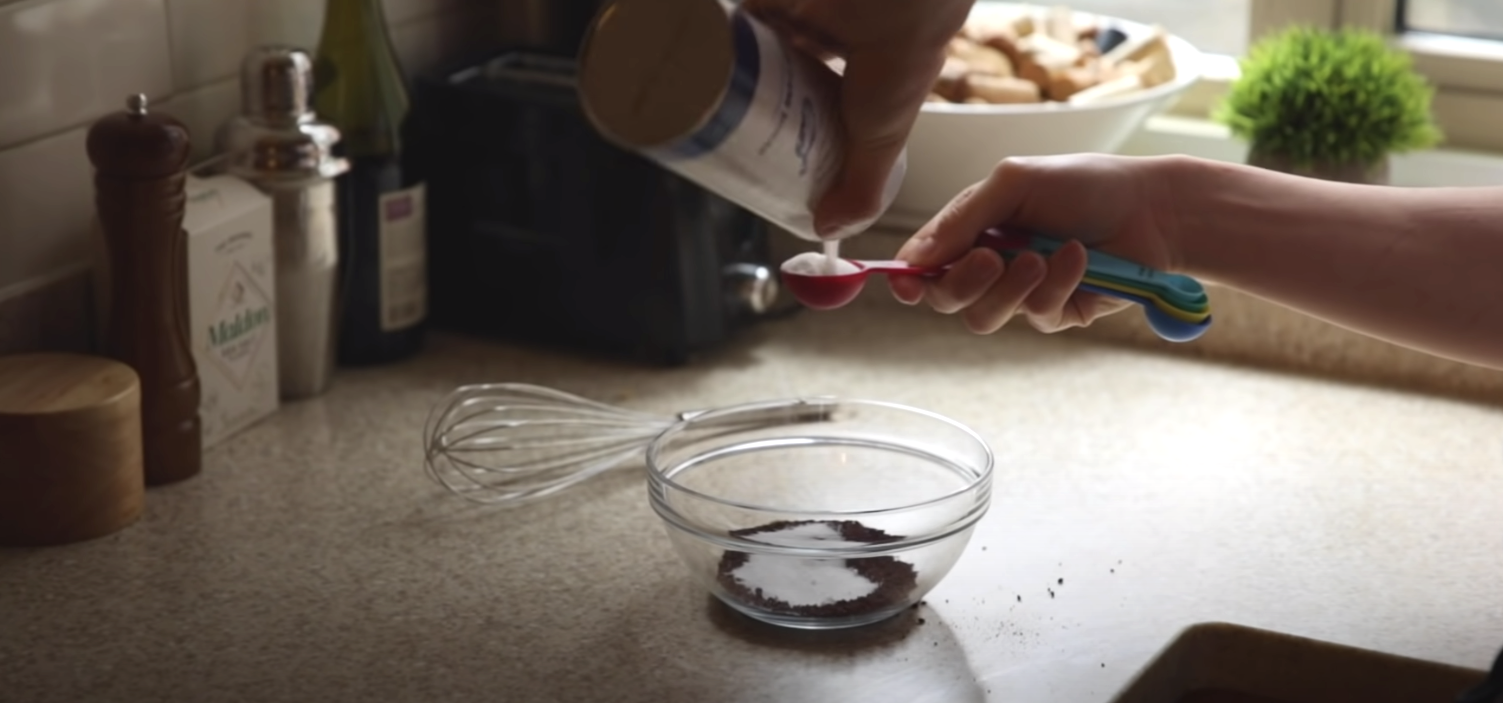 A chef measuring salt in a measuring spoon