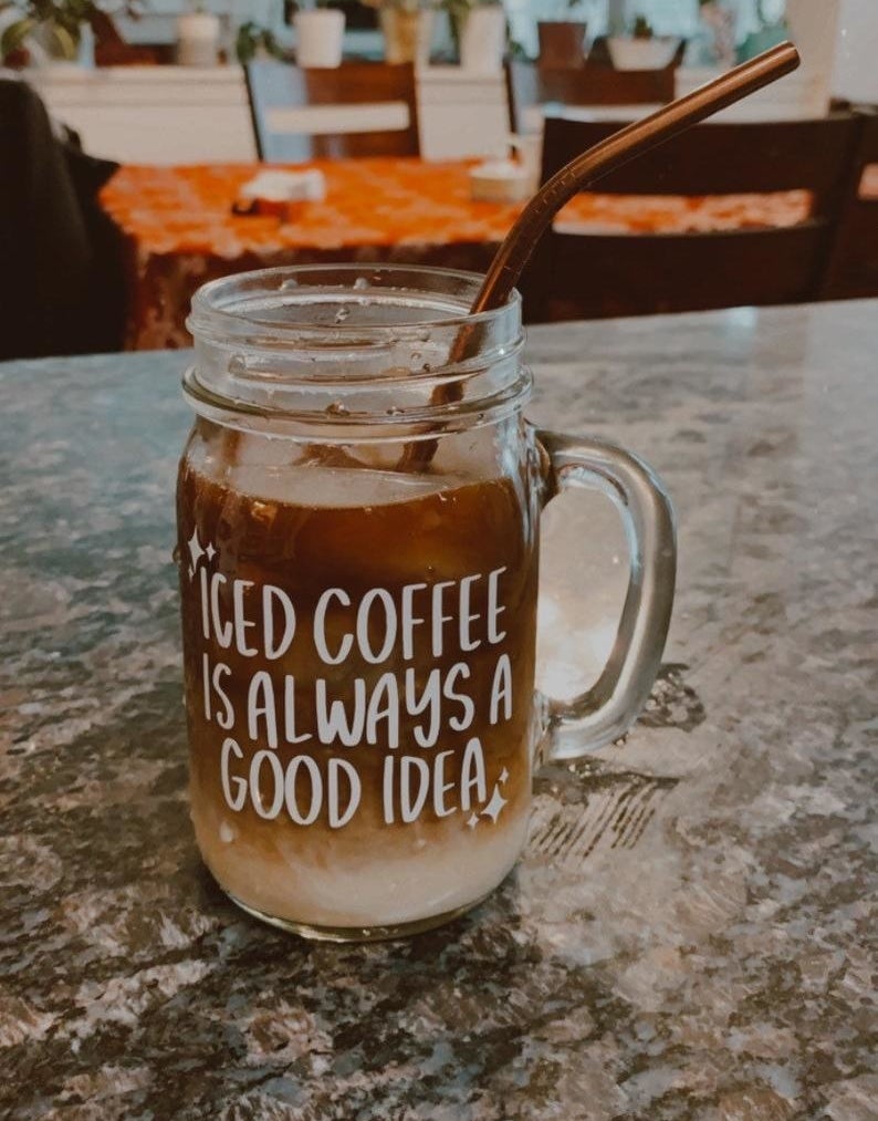 a glass mason jar with a handle a white sticker that says "coffee is always a good idea"