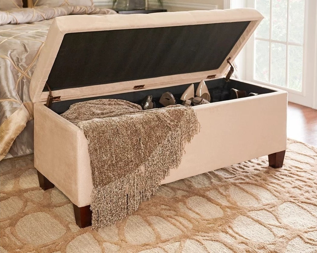 the beige ottoman with a blanket and shoes stored inside